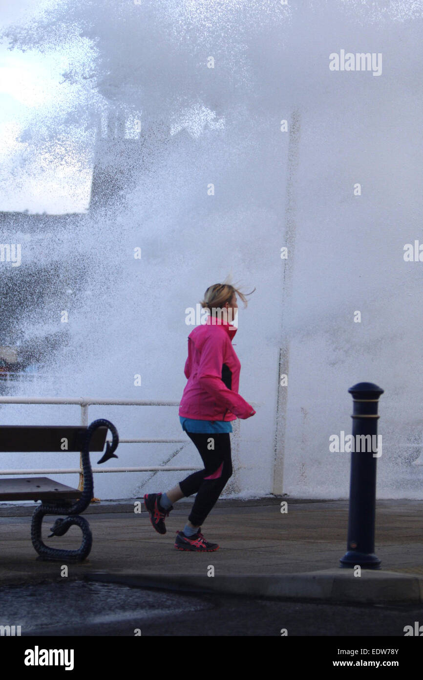 Aberystwyth, Wales, UK. 10th January, 2015. UK weather.  A jogger gets caught out by one of the huge waves smashing into the sea wall in Aberystwyth as storms hit the UK Credit:  Jon Freeman/Alamy Live News Stock Photo