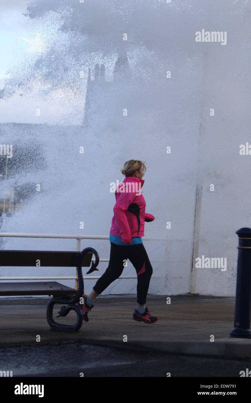 Aberystwyth, Wales, UK. 10th January, 2015. UK weather.  A jogger gets caught out by one of the huge waves smashing into the sea wall in Aberystwyth as storms hit the UK Credit:  Jon Freeman/Alamy Live News Stock Photo