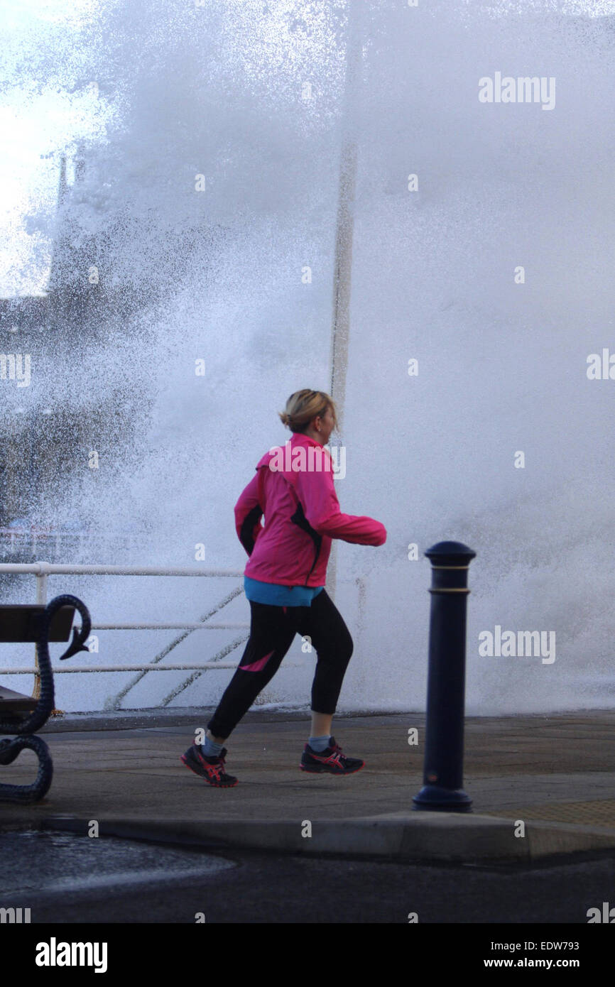 Aberystwyth, Wales, UK. 10th January, 2015. UK weather.  A jogger gets caught out by one of the huge waves smashing into the sea wall in Aberystwyth as storms hit the UK Credit:  Jon Freeman/Alamy Live News Stock Photo