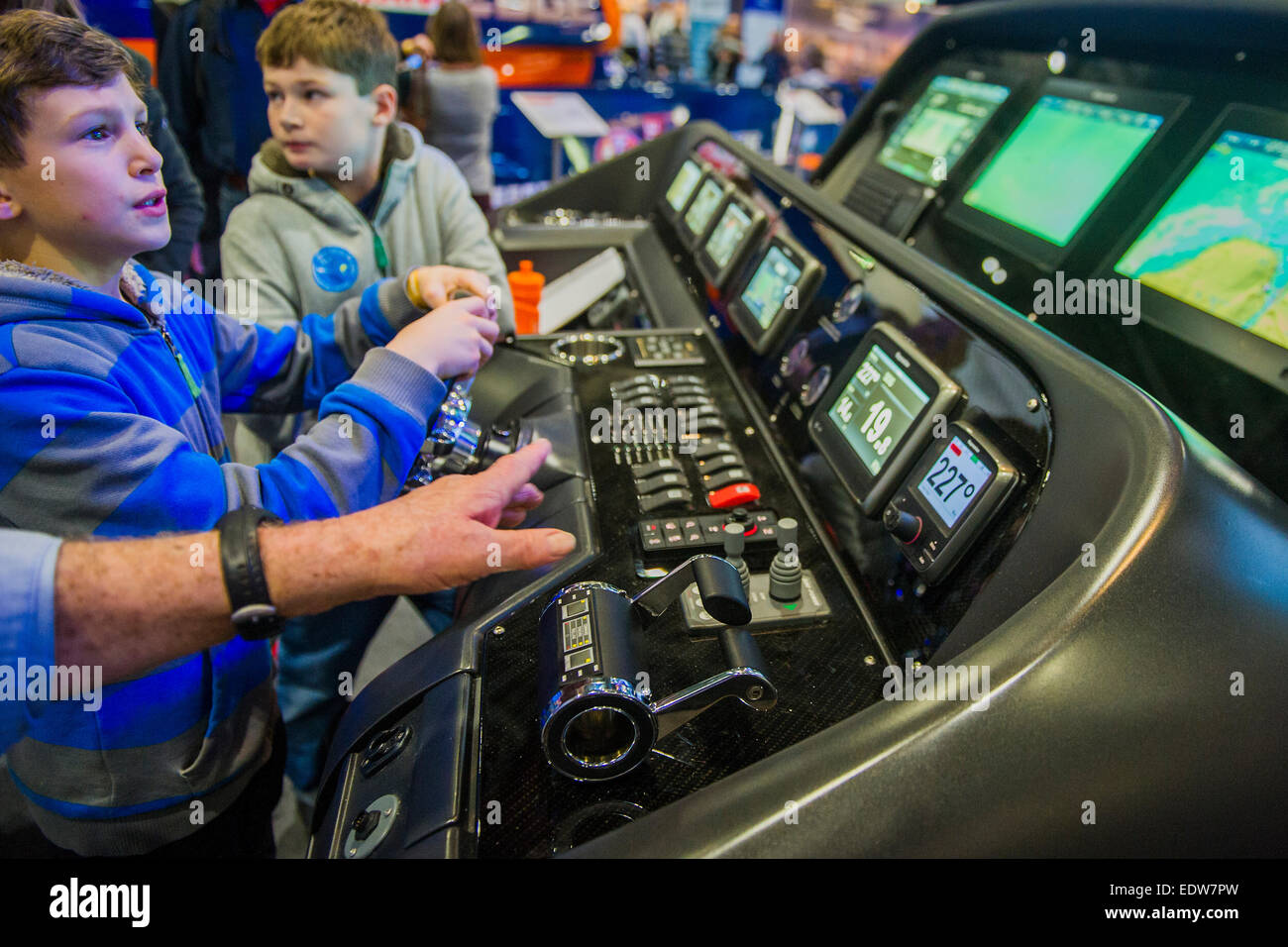 London, UK. 9th January, 2015. Two boys have a go on a sophisticated Raymarine navigation simulator which has been connected to a real driving console from a Sunseeker Predator. The CWM FX London Boat Show, taking place 09-18 January 2015 at the ExCel Centre, Docklands, London. 09 Jan 2015. Credit:  Guy Bell/Alamy Live News Stock Photo