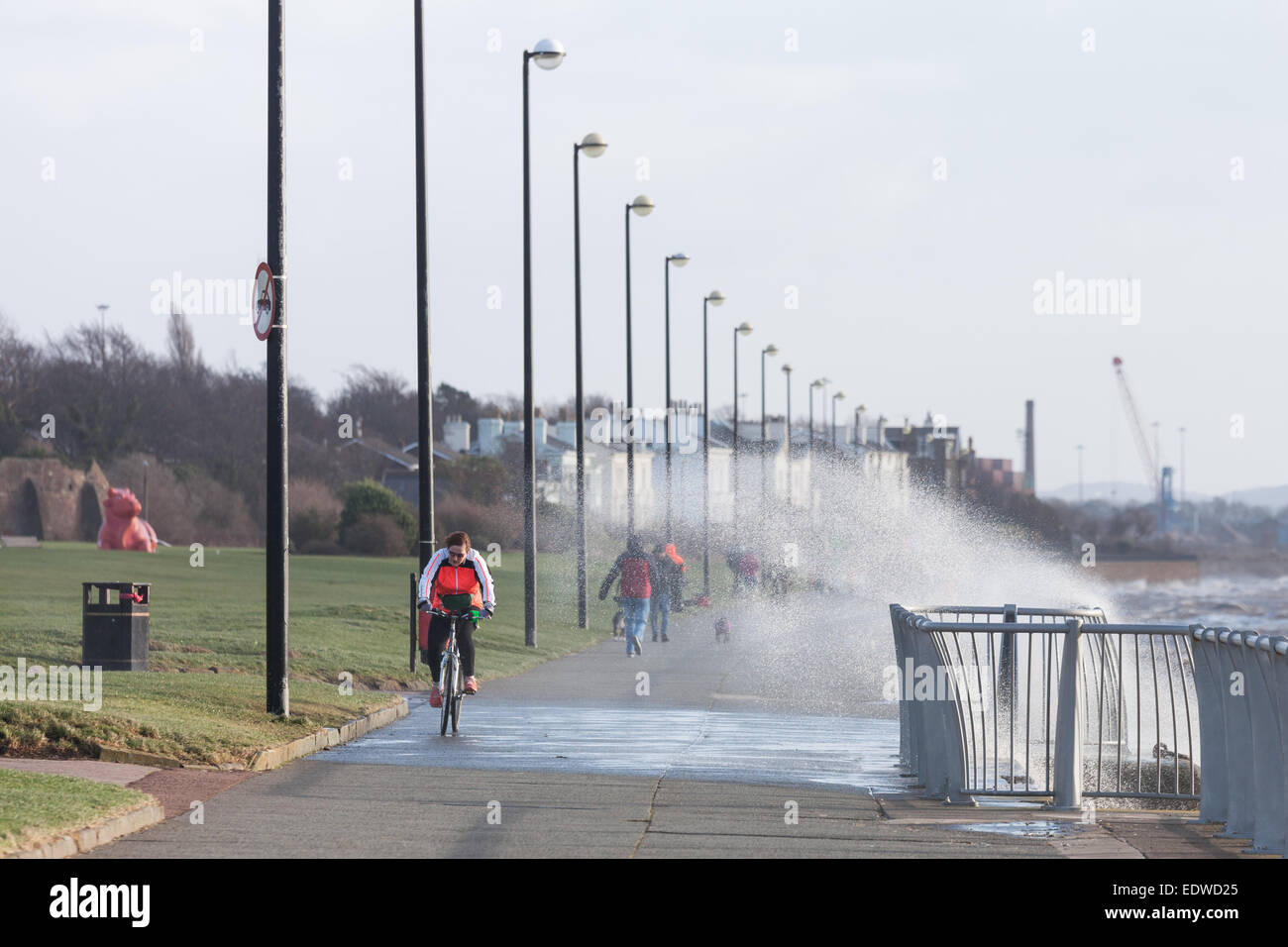 Liverpool, Merseyside, UK. 10th January, 2015. A cyclist is soaked by waves crashing over the promenade at Otterspool in Liverpool during strong winds Credit:  Adam Vaughan/Alamy Live News Stock Photo