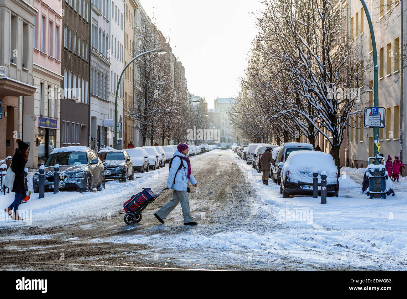 Berlin city street after snow in winter, apartment buildings, snow covered cars and people walking, Bergstrasse, Mitte, Berlin Stock Photo