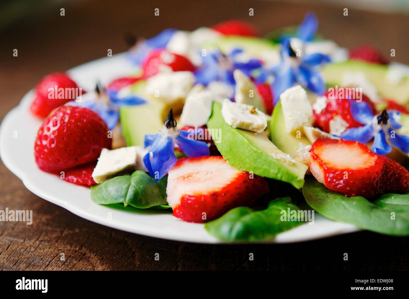 Fresh strawberry, spinach and avocado salad with tofu, soy cheese and borage and elderberry flowers. Stock Photo