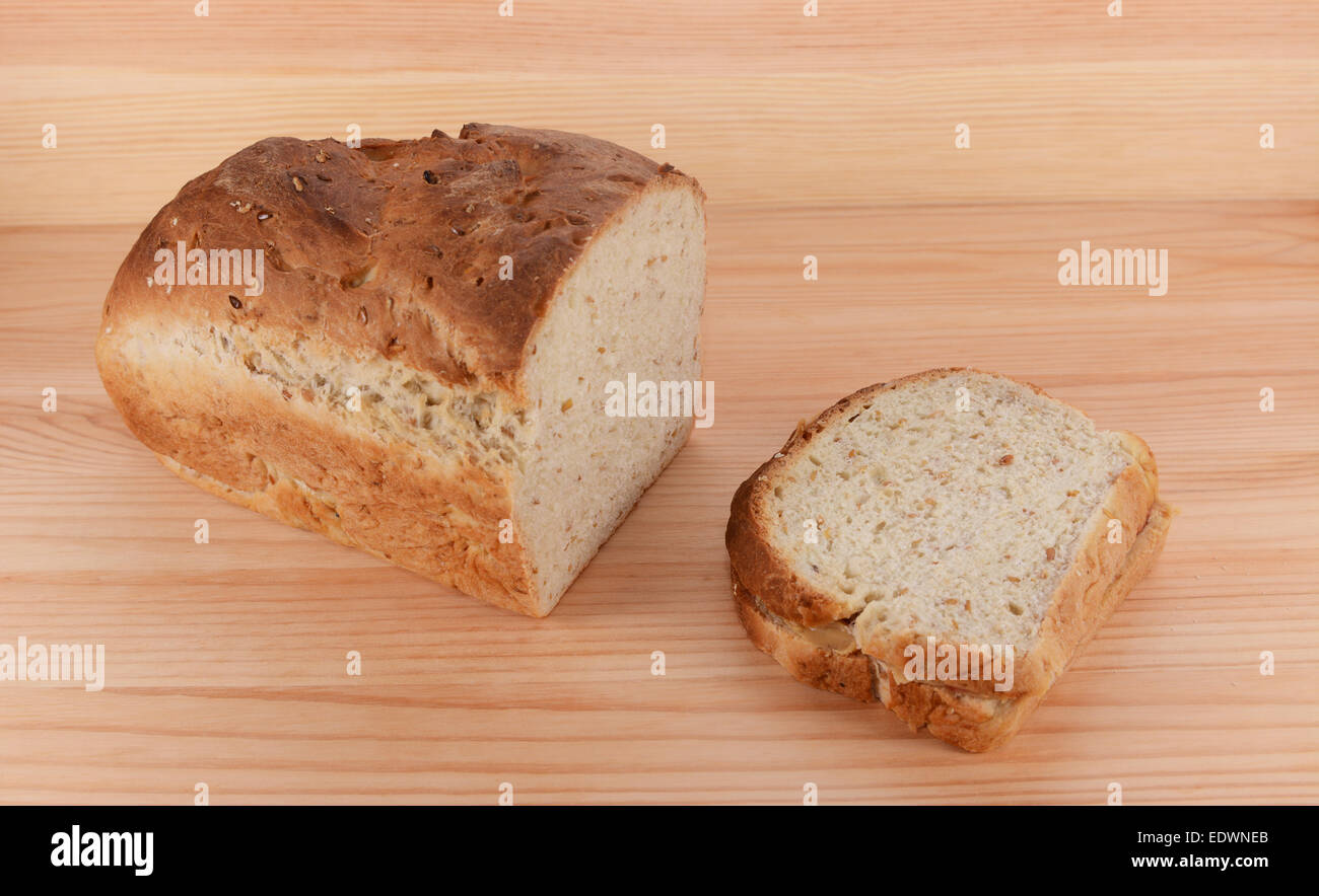 Cut loaf of freshly baked bread with a peanut butter and jelly sandwich on a wooden table Stock