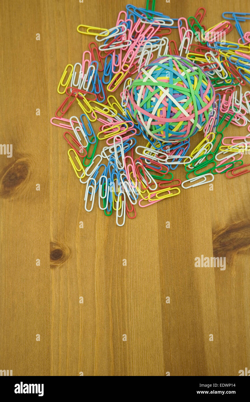 Elevated View of Coloured paper Clips and Rubber band Ball on a wooden table Stock Photo