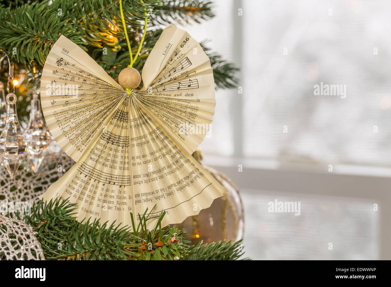 Angel made from folded carol from hymn book on Christmas tree as snow falls  outside the window in the garden and on the trees Stock Photo - Alamy