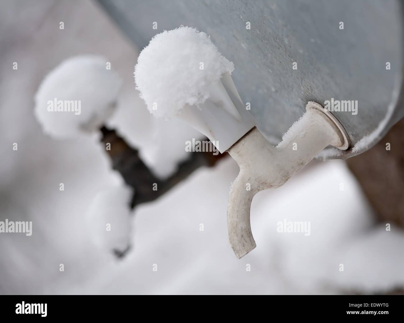 two outdoor metal water supply faucets covered by snow Stock Photo