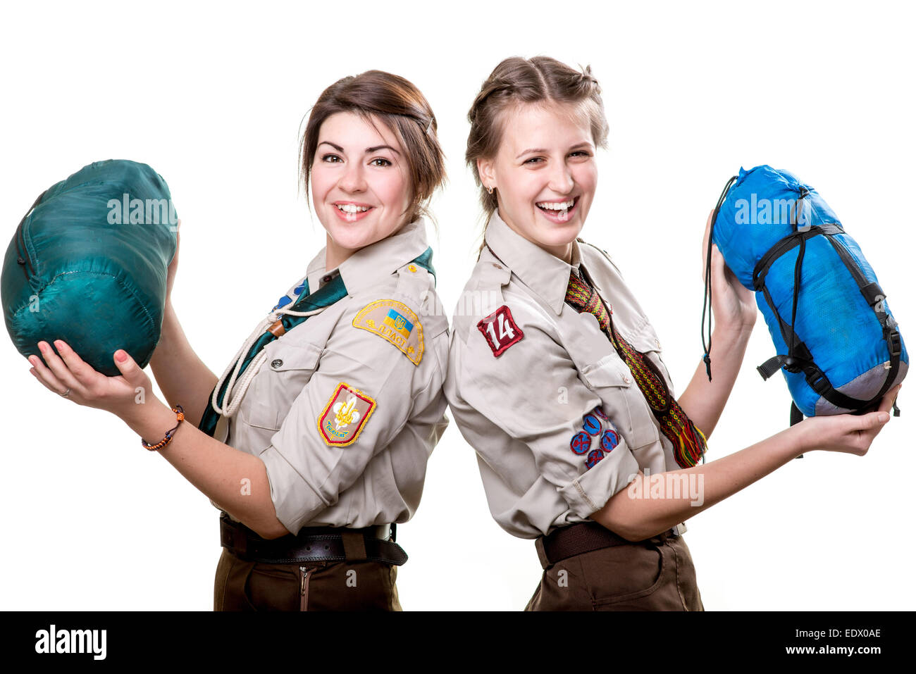 Two young scout girls with sleeping bags isolated on white background