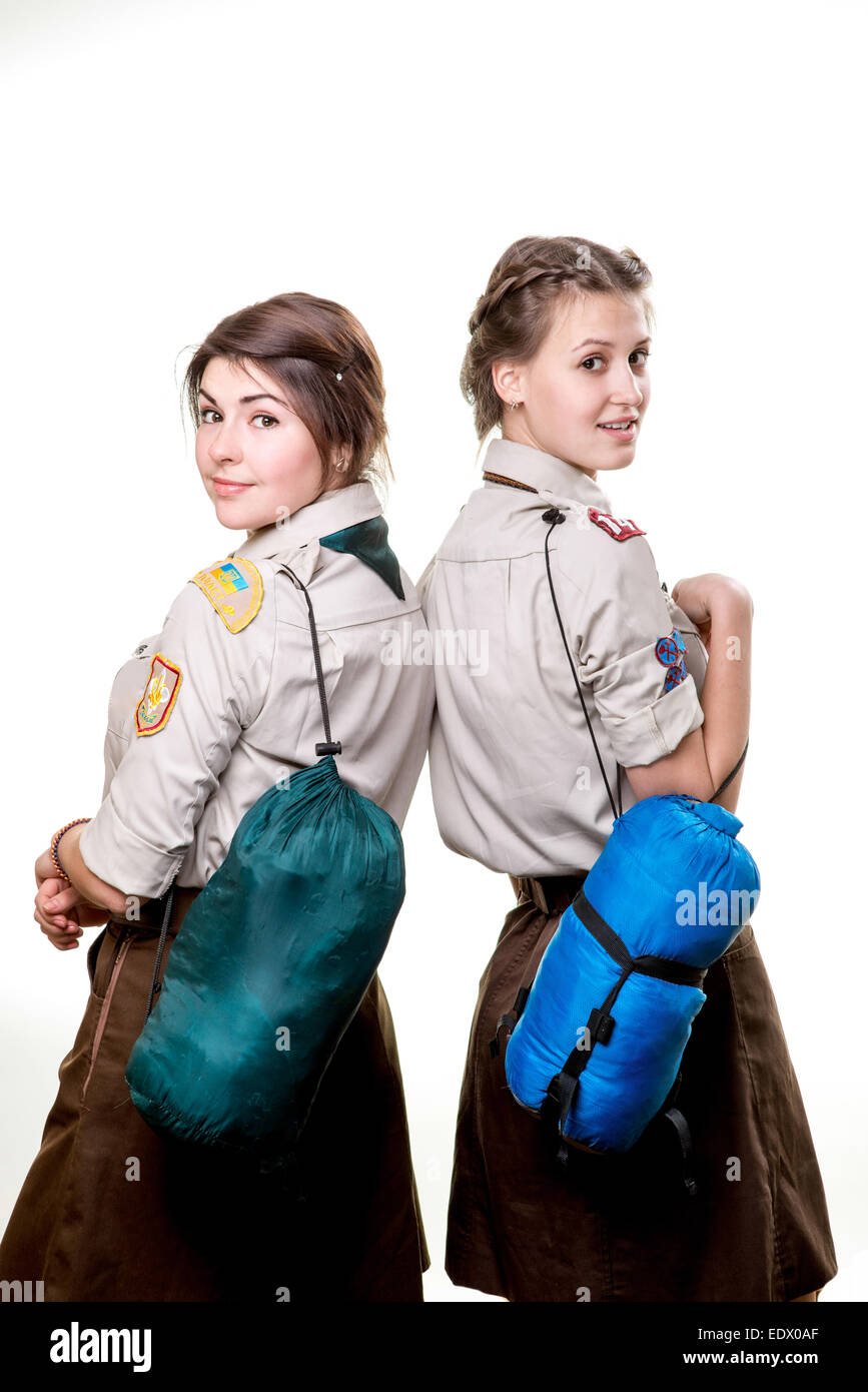 Two young scout girls with sleeping bags isolated on white background
