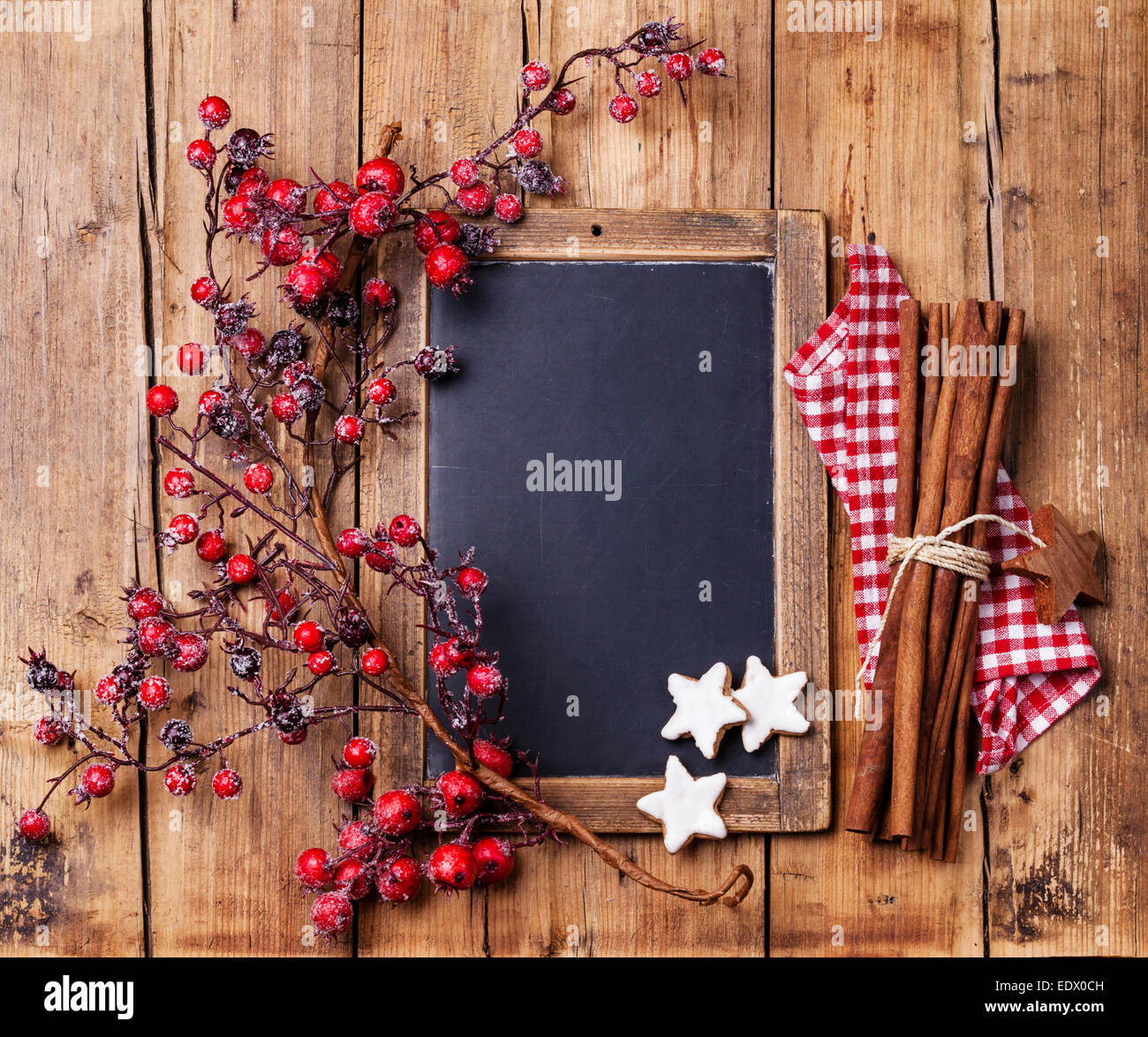 Vintage Christmas background with chalk board, branch with red berries, Xmas cookies and cinnamon sticks Stock Photo