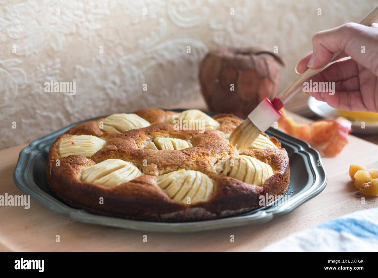 home made apple cake on metal dish, being brushed with honey Stock Photo