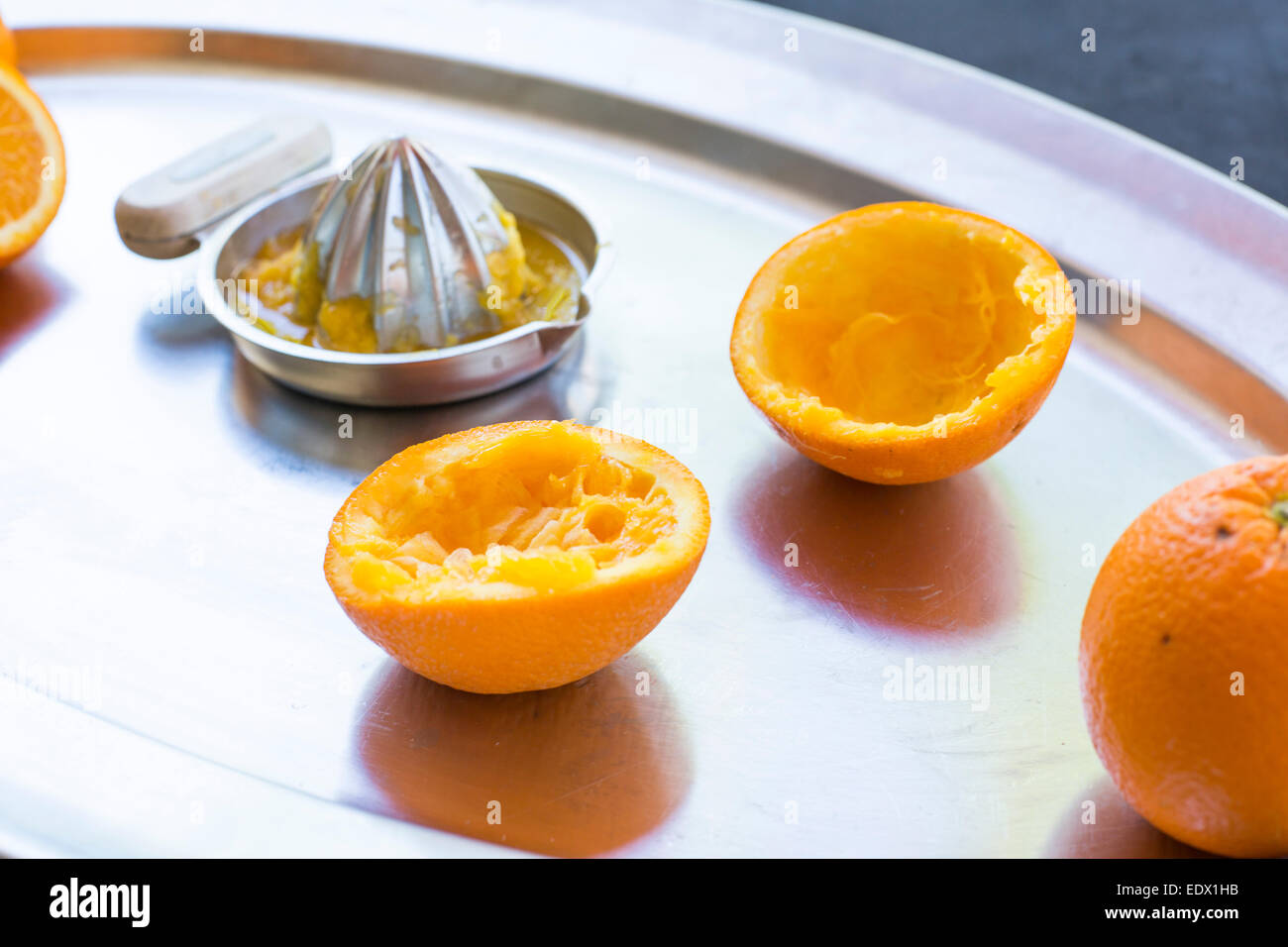 freshly squeezed oranges on a silver tray with silver metal hand juicer. Stock Photo