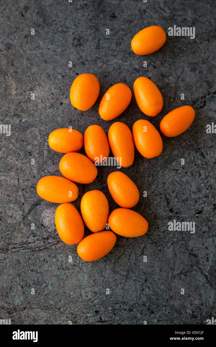 overhead group of kumquats against dark green marble background Stock Photo