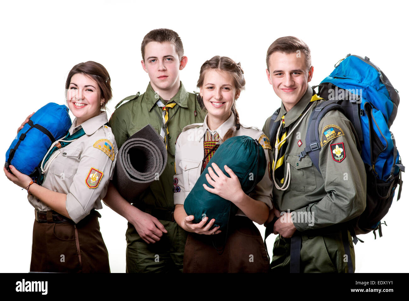 Four young scouts members in uniform with sleeping bags, karemat and