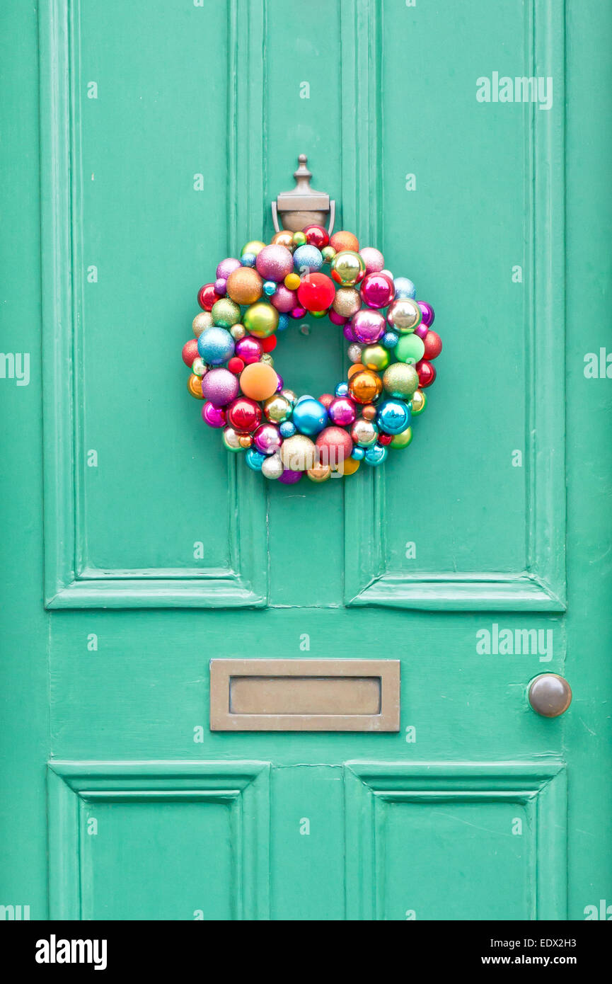 A colorful christmas wreath on a green front door Stock Photo