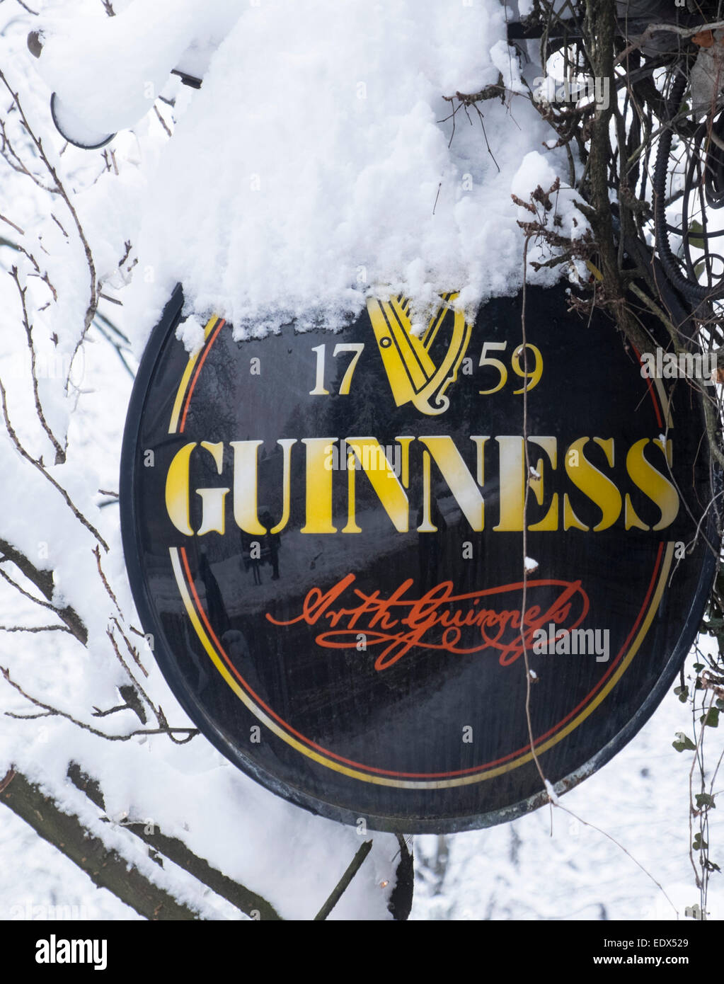 A Guinnes Beer sign covered in snow Stock Photo