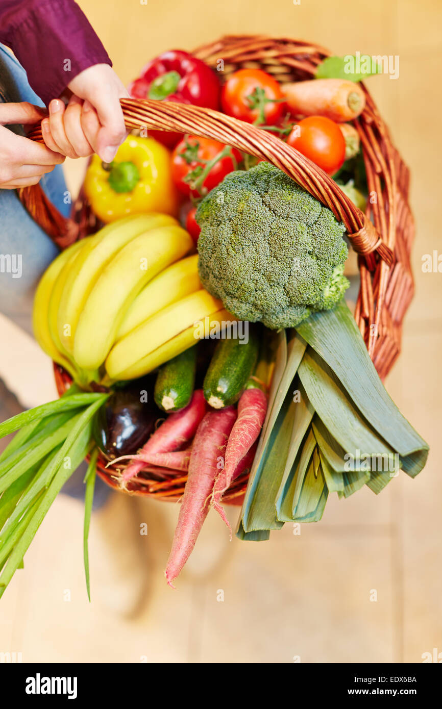 Hands holding a shopping basket full of fresh vegetables and fruits ...