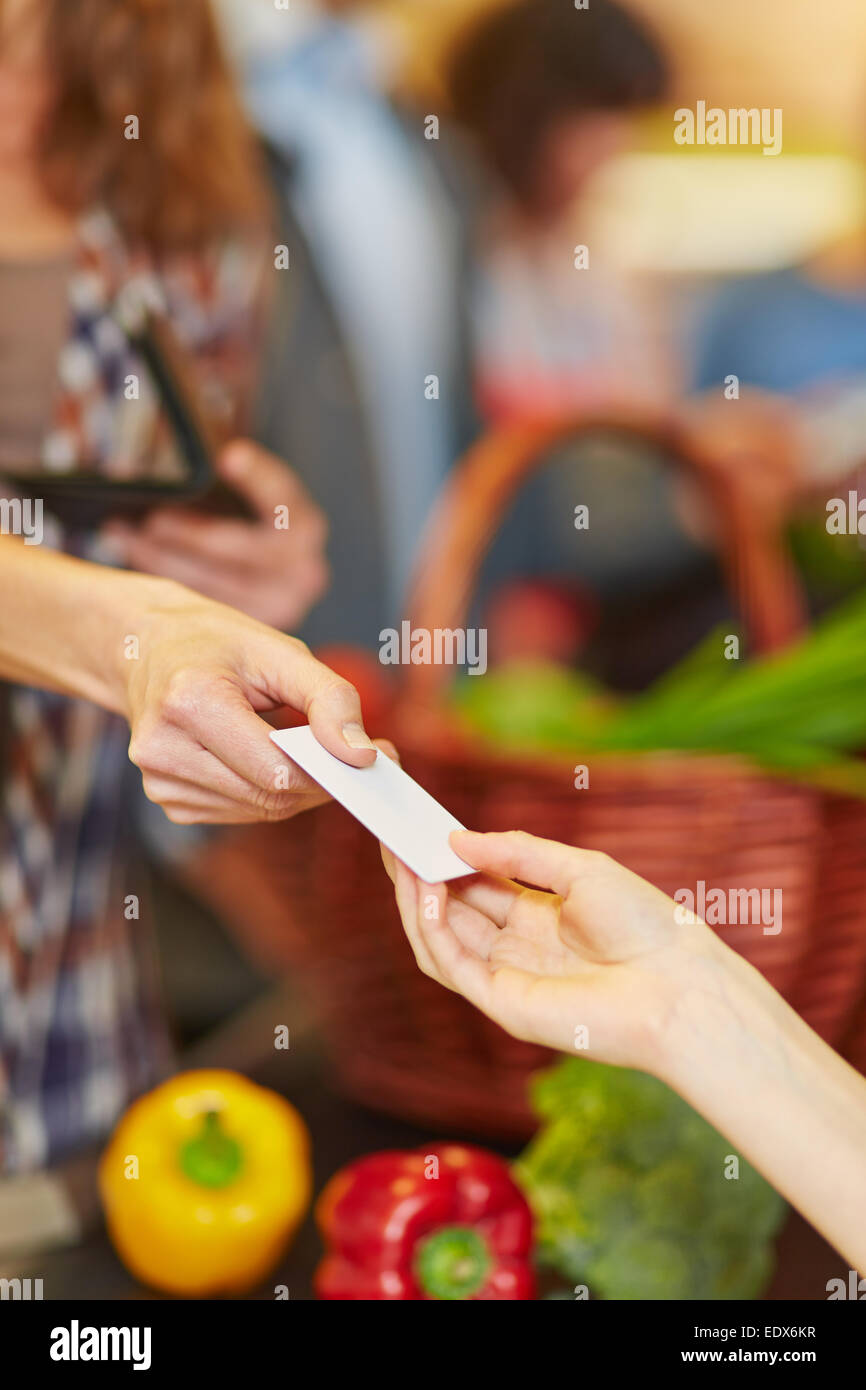 Hand of customer giving credit card to supermarket teller at checkout Stock Photo