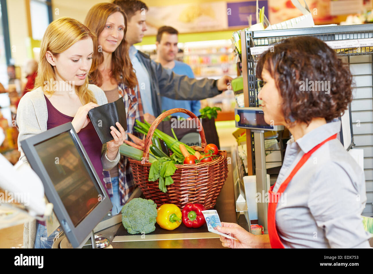 Young woman in supermarket queue is missing money for payment Stock Photo