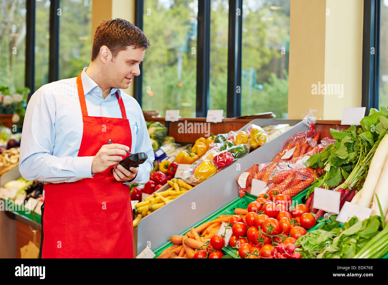 Store manager in supermarket ordering fresh vegetables with mobile data registration terminal Stock Photo