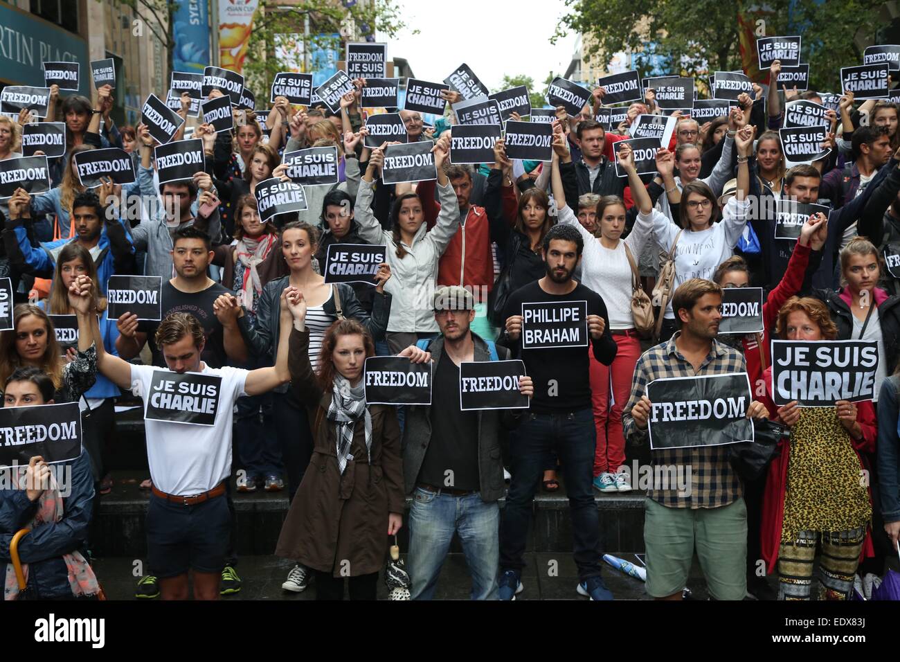 Sydney, Australia. 11 January 2015. French people in Sydney gathered at Martin Place to honour the victims of the Charlie Hebdo attack by Al-Qaeda members. They held signs saying, ‘Freedom’ and ‘Je suis Charlie’. The names of those that had died were read out and a minute’s silence was held. At the end messages were written on a wall. Pictured are French people at the end of the rally as they held hands. Credit: Copyright Credit:  Richard Milnes/Alamy Live News Stock Photo