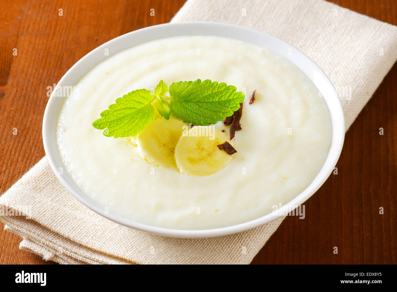 Bowl of smooth milk pudding with sliced banana and grated chocolate Stock Photo