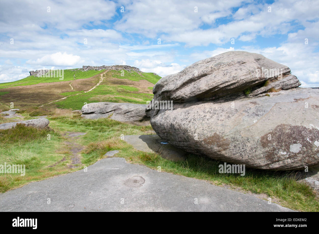 Gritstone boulder in a peak District landscape with view to Higger Tor ...