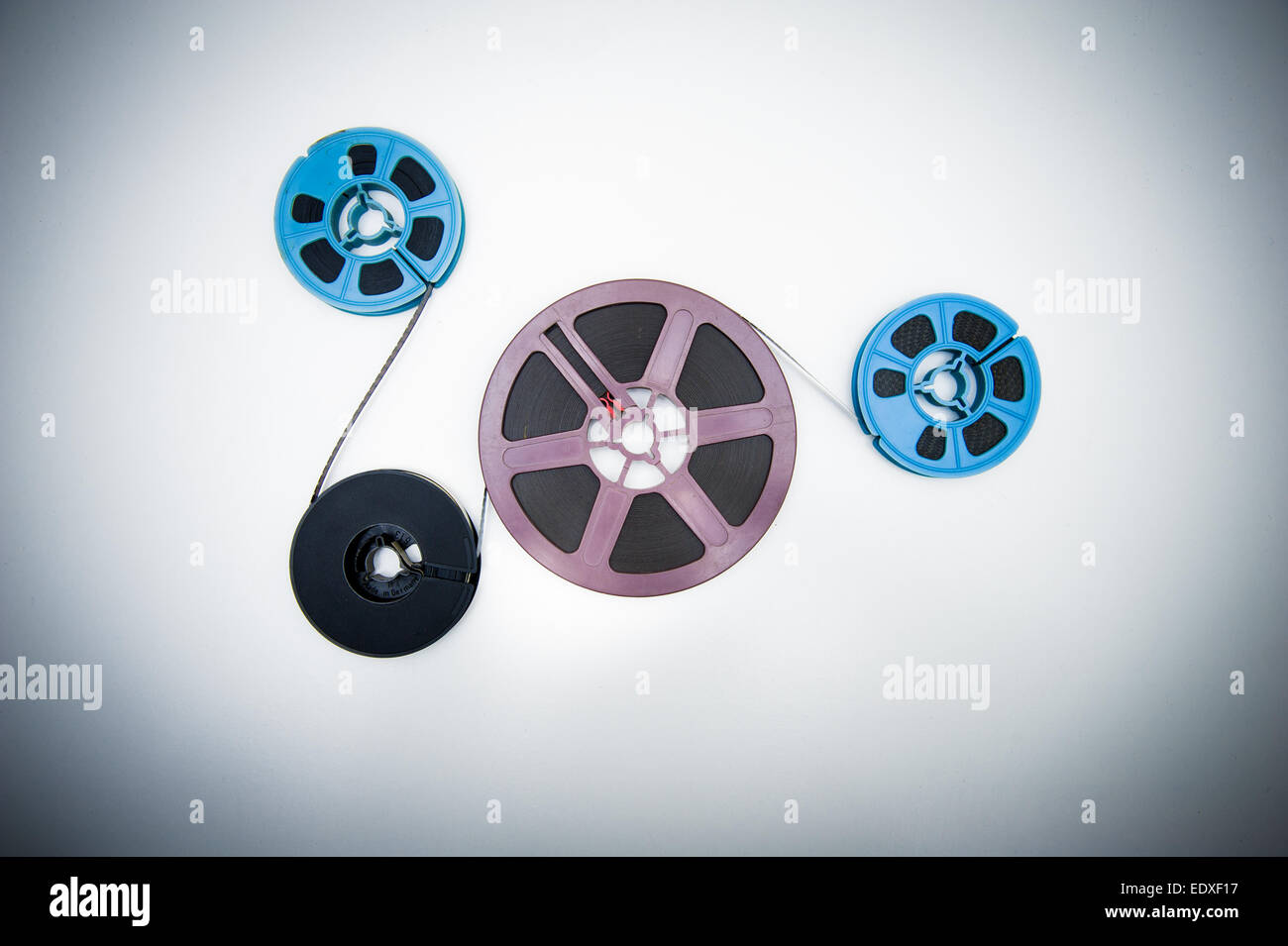 Four big and little size 8mm reels connected with film, vintage color effects Stock Photo