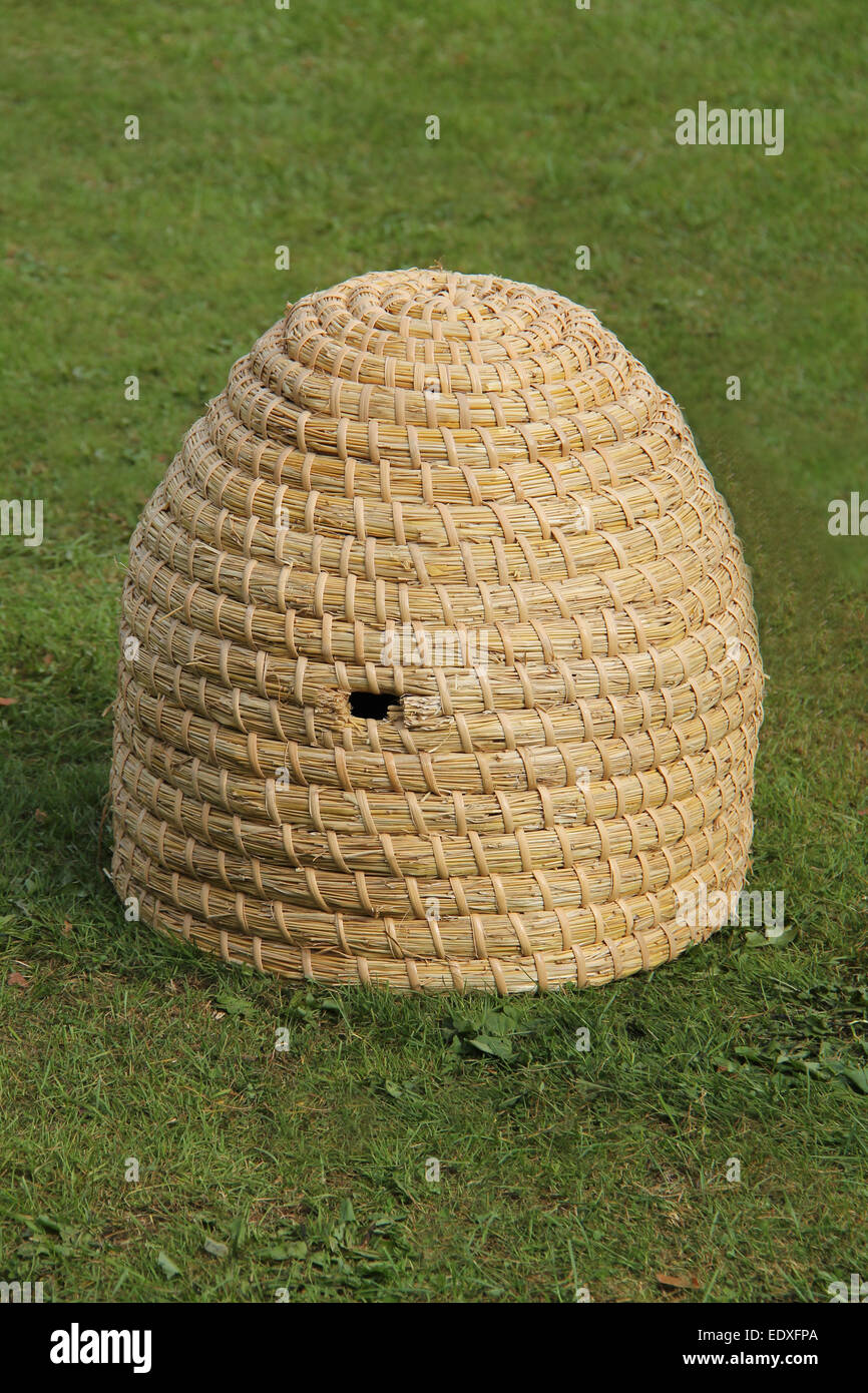 A Wicker Made Natural Material Beehive on Grass. Stock Photo