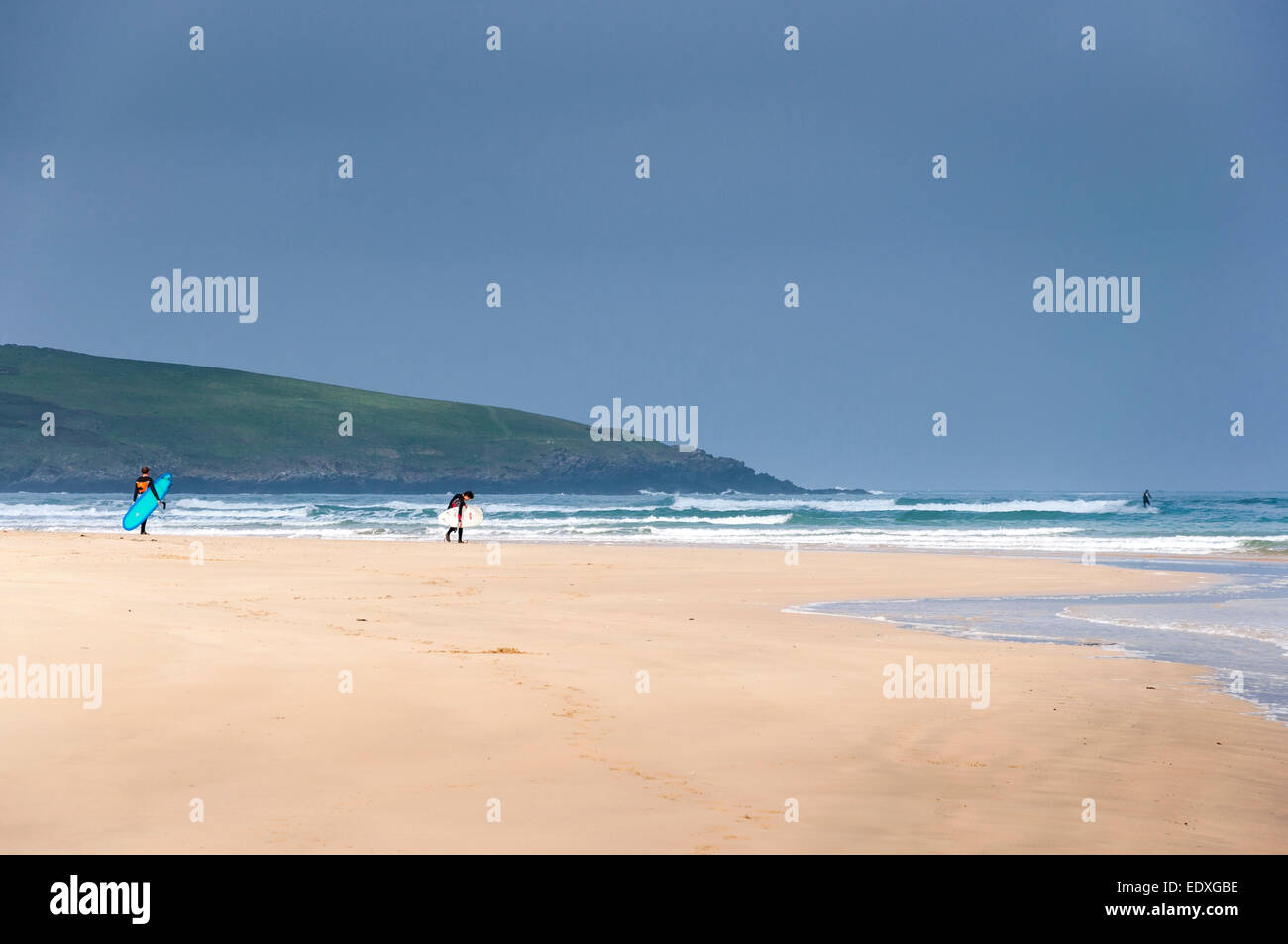 Surfers making their way to the sea, carrying their boards on Crantock beach near Newquay, Cornwall. Stock Photo