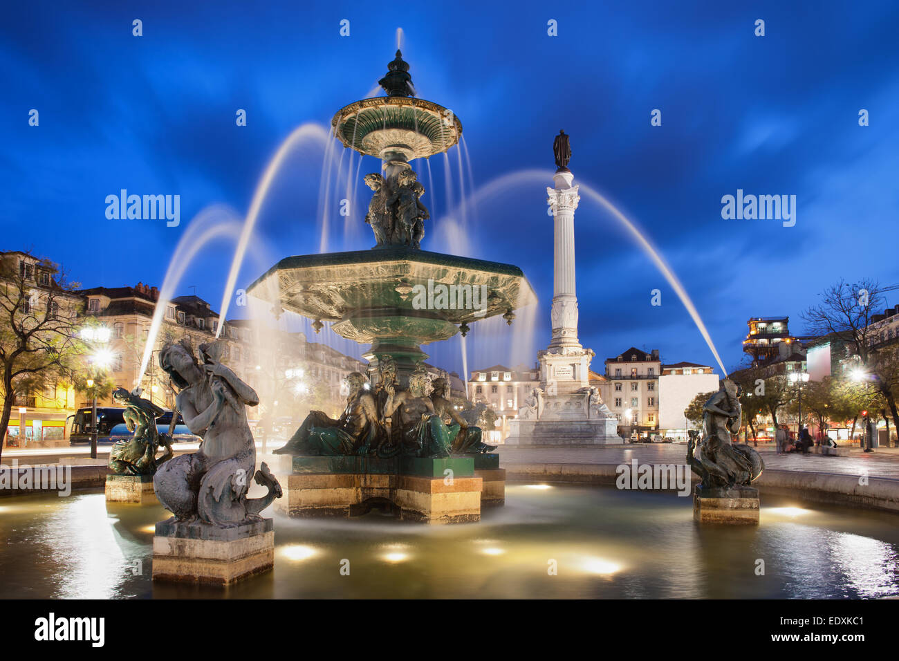 Fountain on Rossio Square at night in Lisbon, Portugal. Baroque style artwork with mythical creatures sculptures. Column of Dom Stock Photo