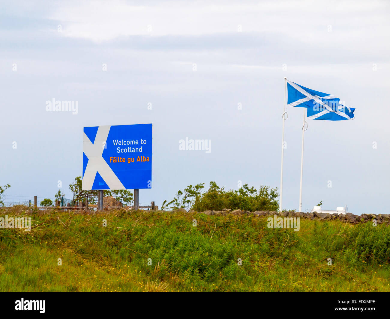 Welcome to Scotland road sign in English and Gaelic languages and Scottish Saltire flags at Carter Bar on the border. Stock Photo