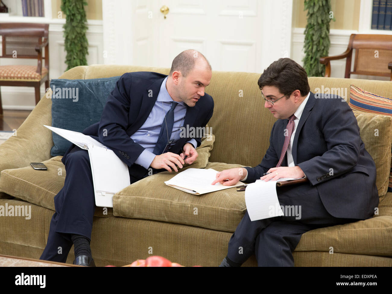 Deputy National Security Advisor Ben Rhodes, left, confers with Ricardo Zuniga, National Security Council's Senior Director for Western Hemisphere Affairs, during President Barack Obama's phone call with President Raúl Castro of Cuba, in the Oval Office, Dec. 16, 2014. Stock Photo