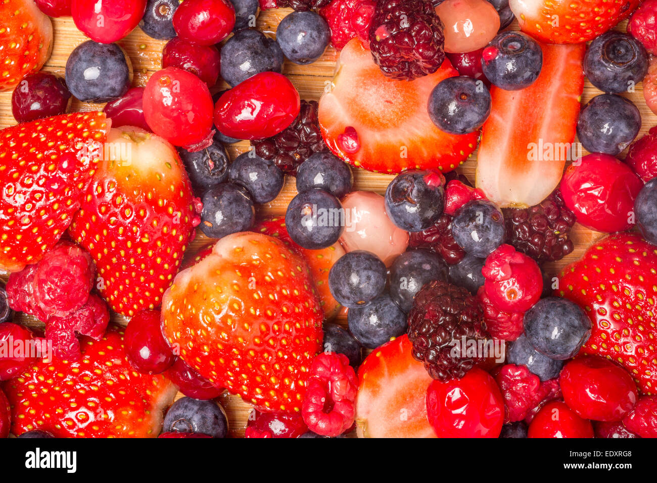 Mixed berries viewed from above as they lie spread out on a bamboo cutting board. Stock Photo
