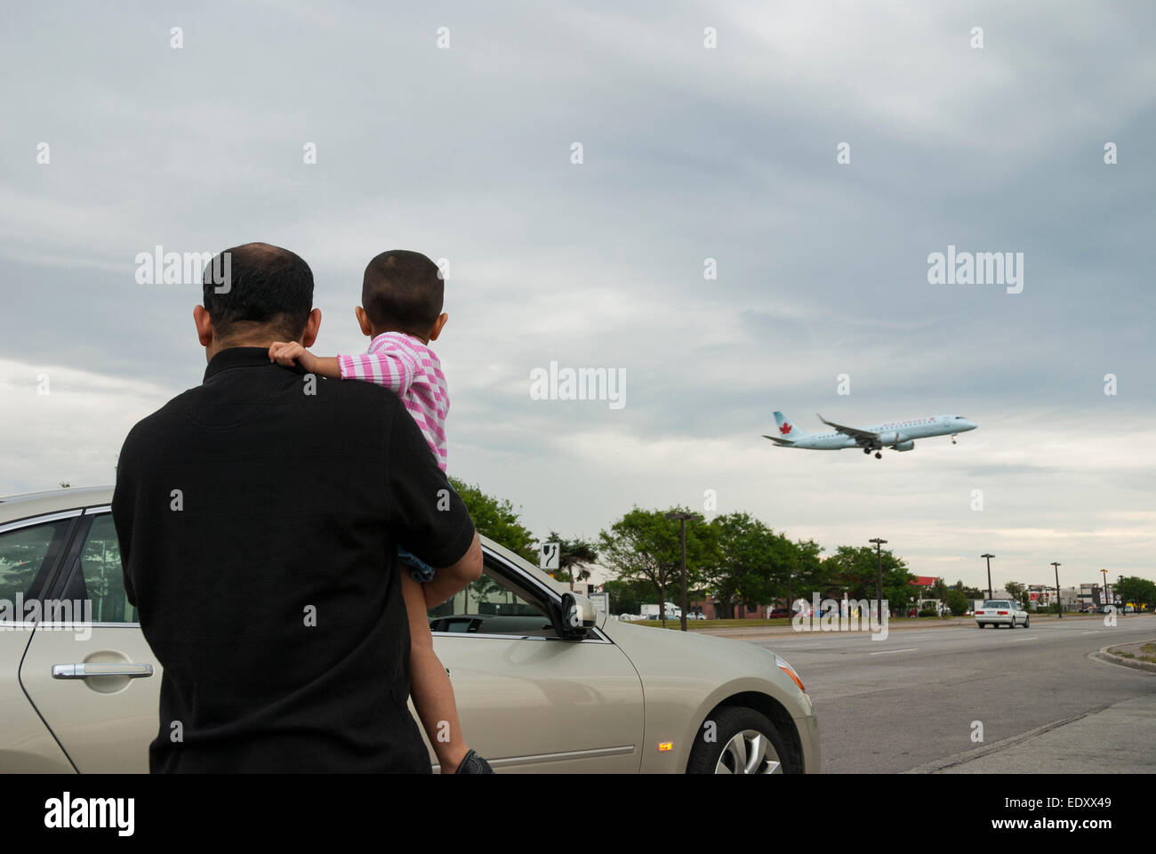 A father and his young son watch low flying planes landing from the