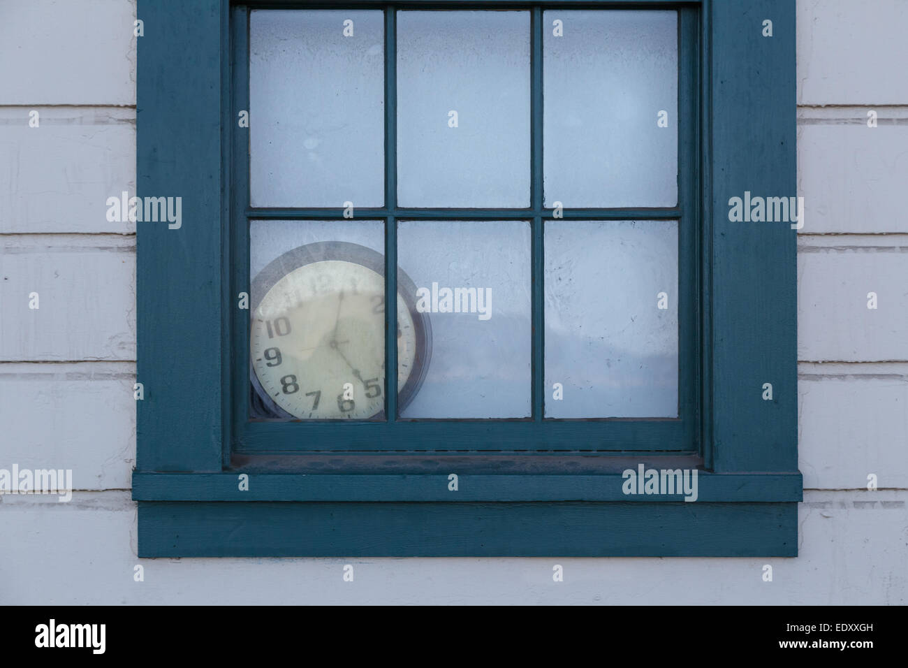 An old clock lies forgotten behind a window. Stock Photo