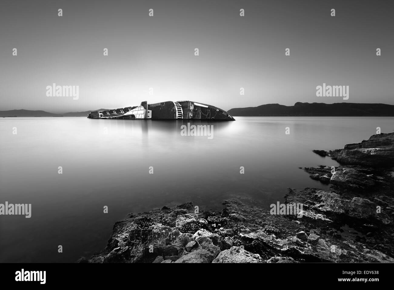 Mediterranean Sea shipwreck leaning on one side near a rocky coast Stock Photo