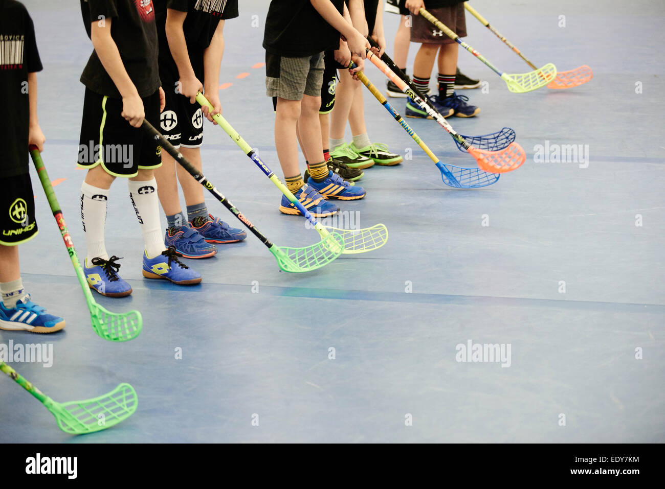 Children boys schoolchildren playing floorball (floor hockey) match in school gym hall with
