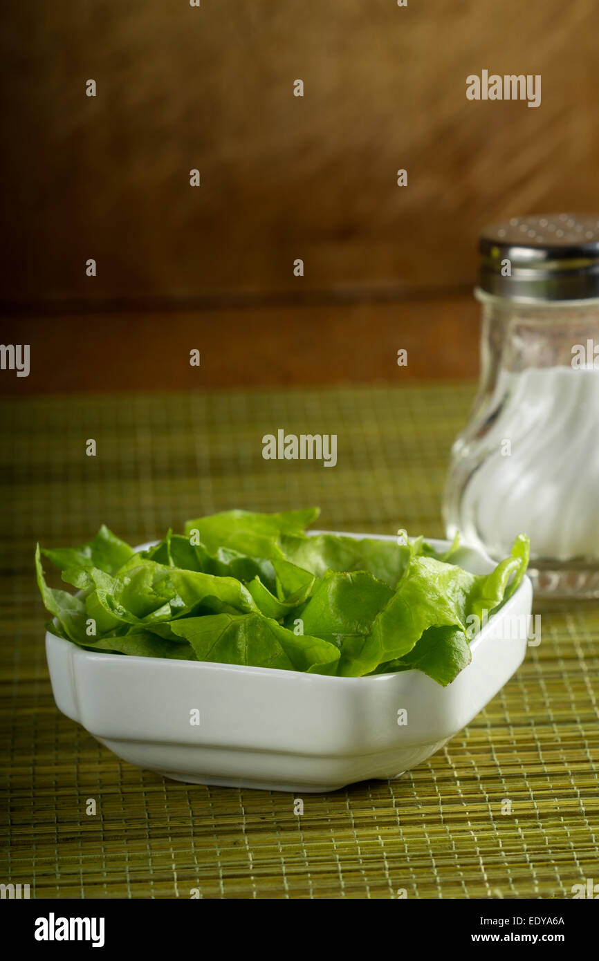 Fresh salad in white bowl over green bamboo rug Stock Photo