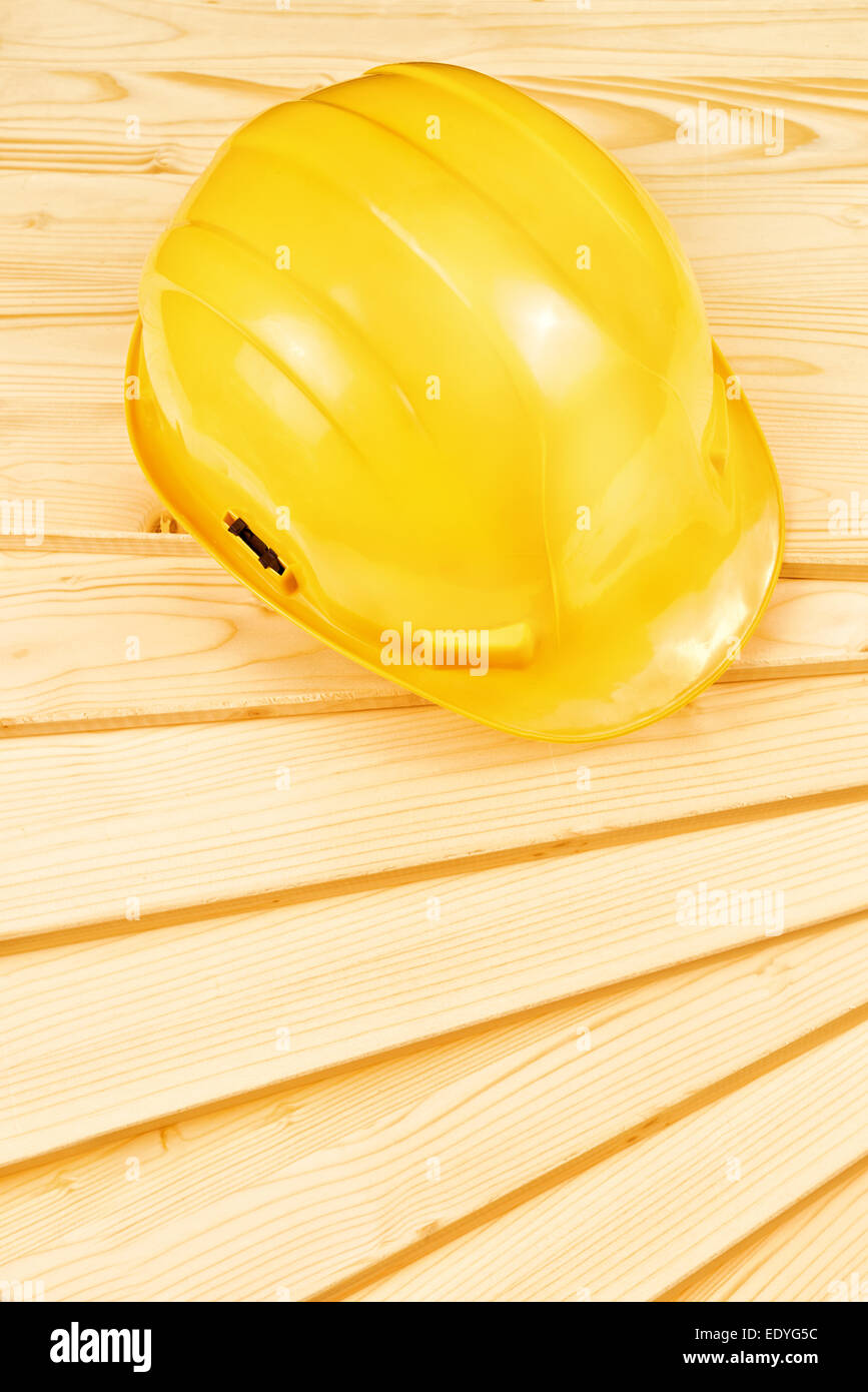 Yellow hardhat on pine wood planks as copy space for carpentry job concept Stock Photo