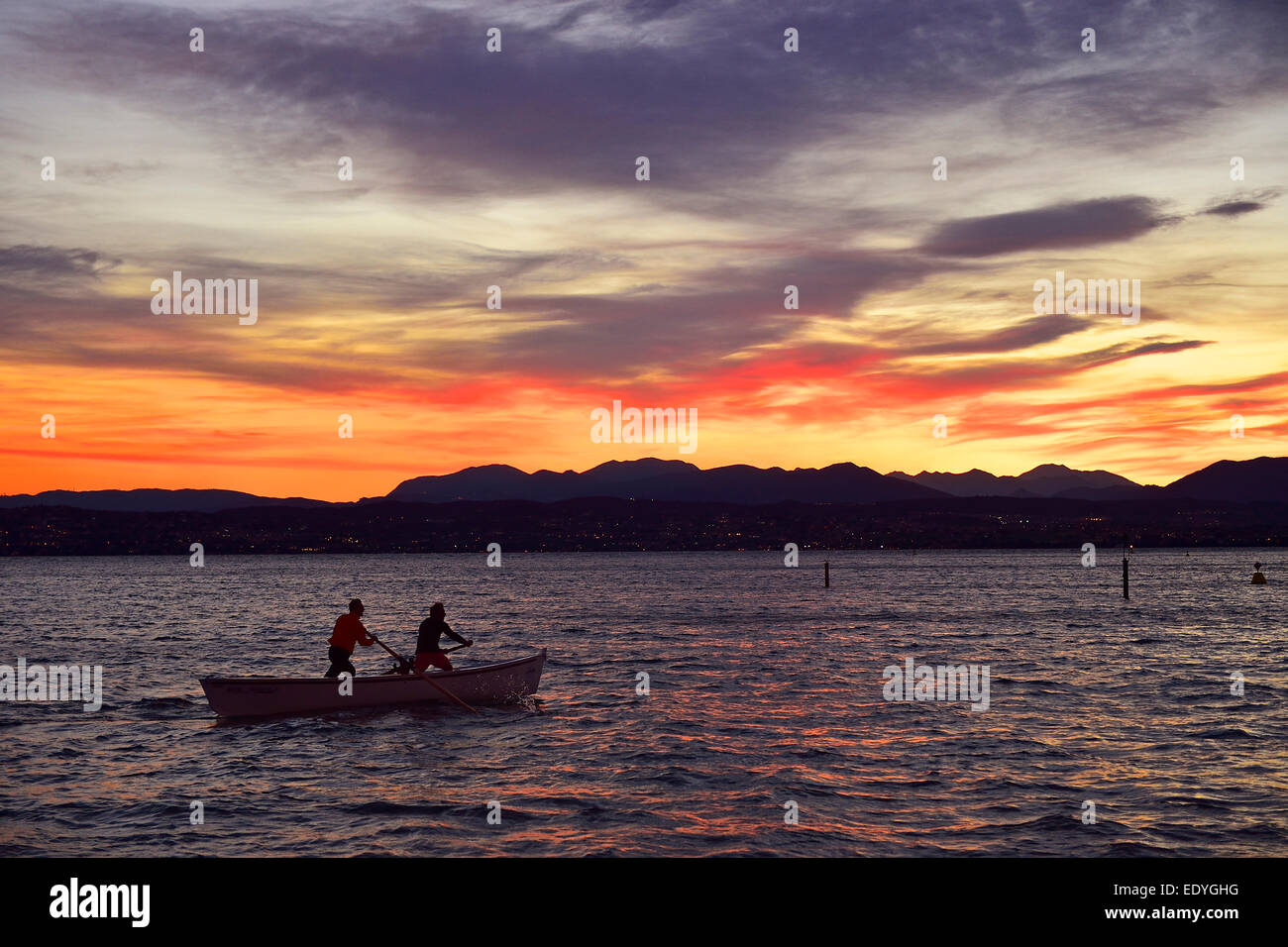 People on a boat in Lake Garda, Lago di Garda, with sunset, Desenzano del Garda at the back, Sirmione, Lombardy, Italy Stock Photo