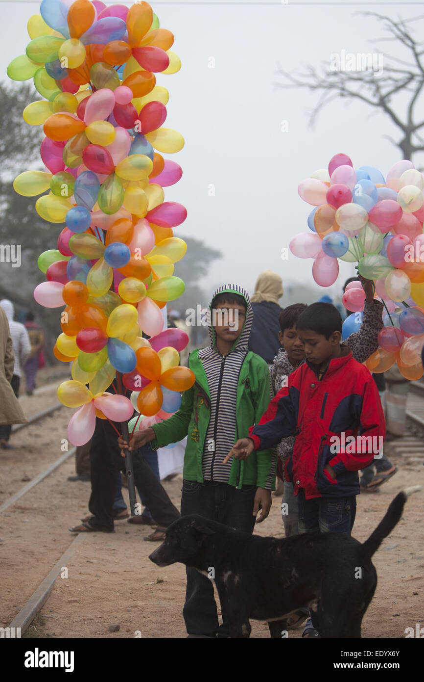 Dhaka, Bangladesh. 11th Jan, 2015. Bangladeshi boy carries balloons for sale as he watches Muslim devotees walk to attend the final prayer of the three-day Islamic Congregation on the banks of the River Turag in Tongi, 20 kilometers (13 miles) north of the capital Dhaka. Hundreds of thousands of Muslims attended the annual three-day event that is one of the world's largest religious gatherings being held since 1960's to revive Islamic tenets. It shuns politics and calls for peace. © Zakir Hossain Chowdhury/ZUMA Wire/Alamy Live News Stock Photo