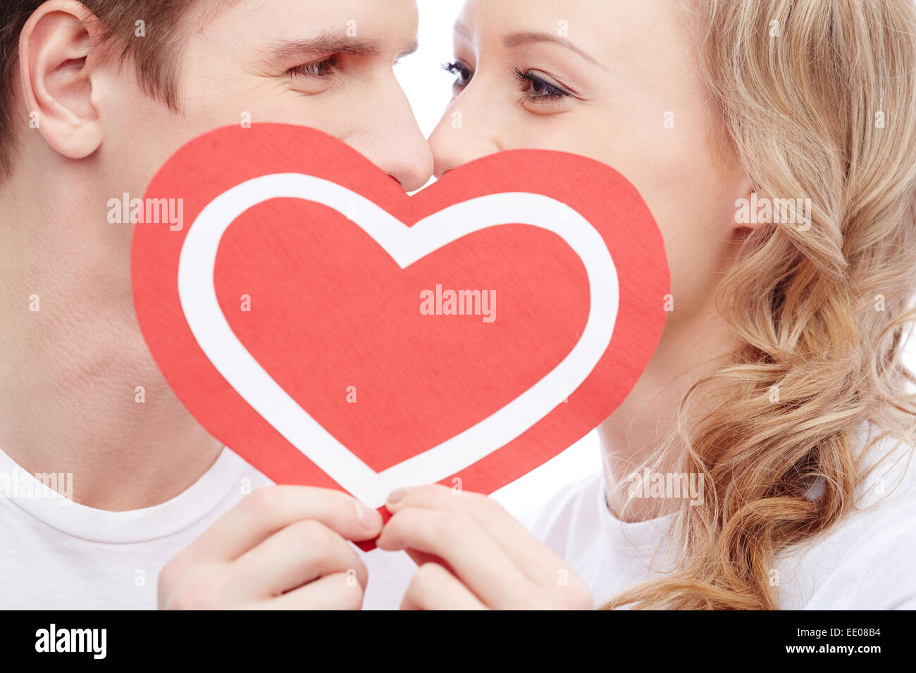 Young people kissing behind paper heart Stock Photo - Alamy