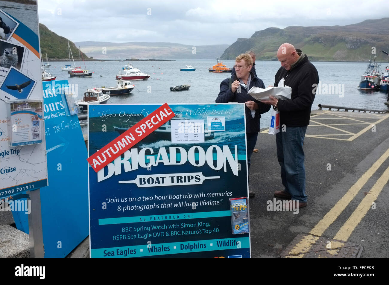 Portree Harbour, Isle of Skye, Scotland. A couple eat fish and chips whilst waiting for a Brigadoon boat trip Stock Photo