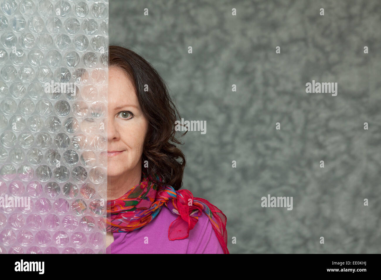 Smiling Woman half hidden by a textured wall, with Copy Space Stock Photo