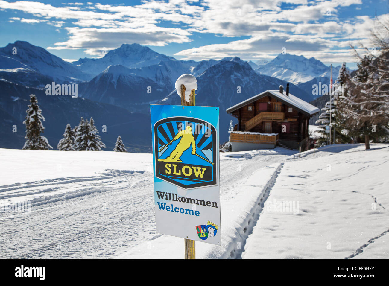 Welcome sign urging skiers to skiing slowly in Alpine ski station in the Swiss Alps in winter Stock Photo