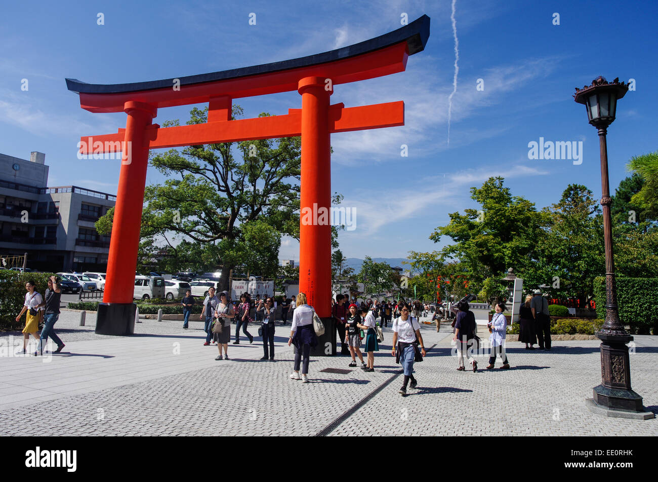 Tourists walking through the red torii at the entrance of Fushimi Inari ...