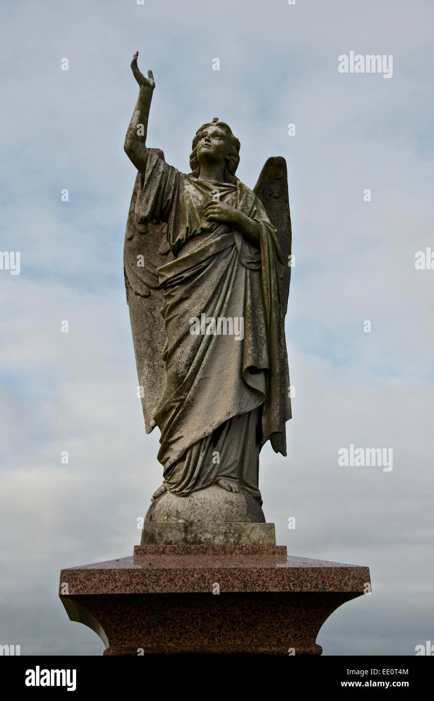 Carved angel on a marble plinth with arm extended upwards. Stock Photo