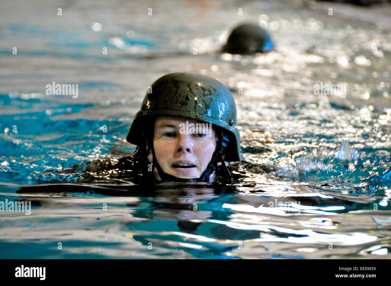 US Army Officer Candidate Wendy McDougall swims wearing full combat uniform and helmet during water survival training January 10, 2015 in Rehoboth Beach, Delaware. Stock Photo