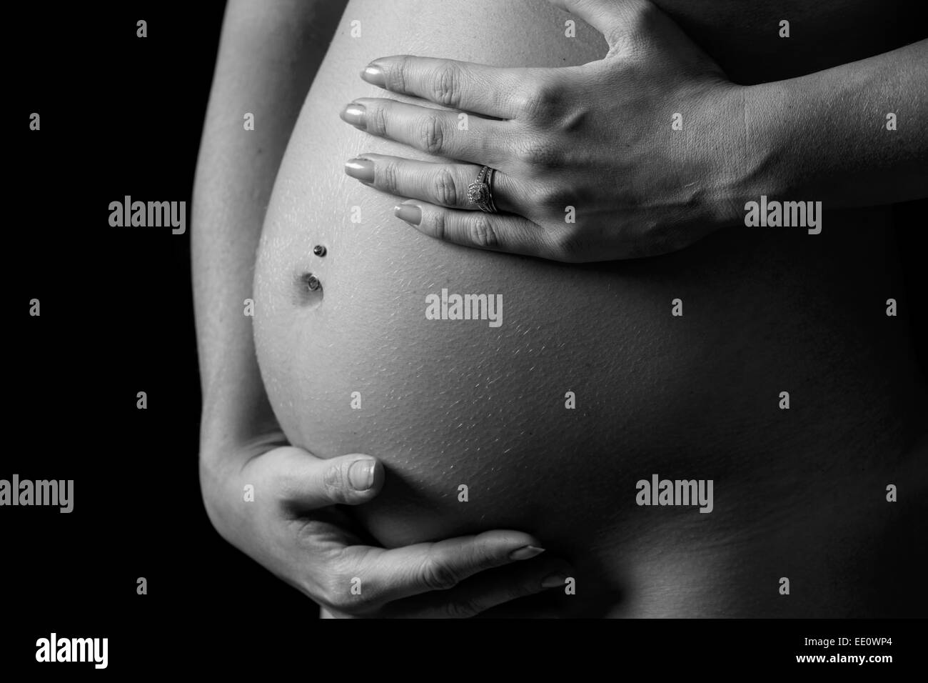 A woman holds her hands on her stomach or bump whilst pregnant. Stock Photo